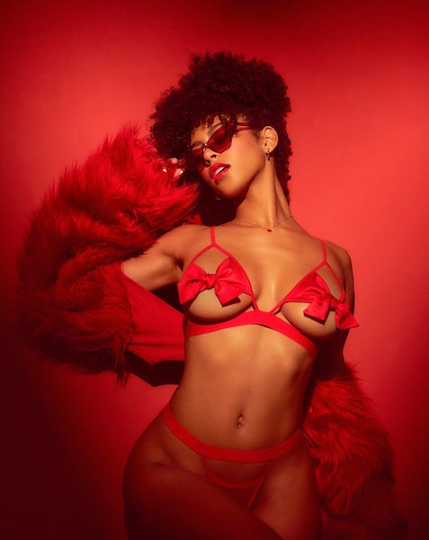 Woman in red lingerie with a red feathered boa against a red background