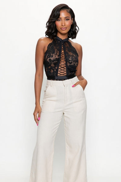 Woman wearing a black lace top bodysuit and white pants